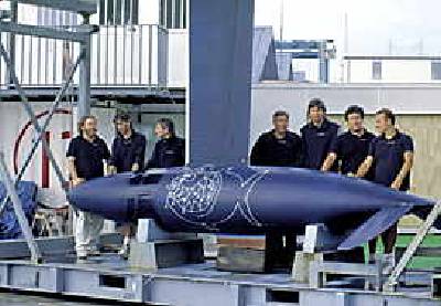 Dave Egan (fourth from the left) and a few members of the design team behind the winged keel of the Team Prada boat on the dock in Auckland.
